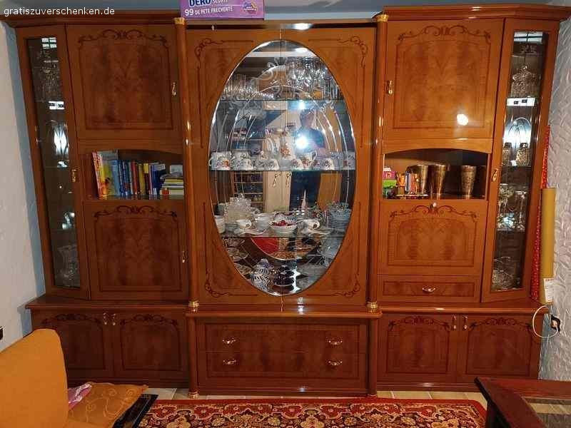 Wohnzimmer Schrank im italienischen Stil. Wohnzimmer Schrank im italienischen Stil. Sehr gut erhalten. Keine Kratzer, keine Fehler Maße: 3m breit 2,21 hoch, wenn der ovale Kranz aufgesetzt wird (derzeit nicht auf dem Bild) Farbe ist rotbraun, Furnier, mit Einlagen. 6 Korpus-Teilen zzgl. Türen, Kranz, Glas- und Holzeinlage-Böden. Geschirr, Kristall-Gläser etc. können wir gerne zum Teil mit verschenken